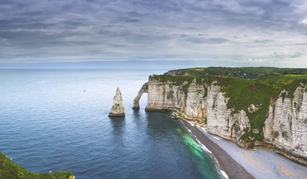 Etretat Aval cliff, rocks and natural arch landmark and blue ocean. Aerial view. Normandy, France, Europe.